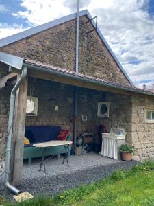 a stone house with a blue couch and a table at Au Petit Paradis in Saint-Domet