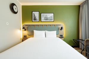 a bedroom with a large bed and two pictures on the wall at Campanile PRIME - Lublin in Lublin