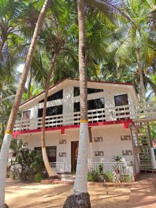 a house with palm trees in front of it at Samant Beach Resort in Malvan
