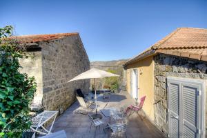 a patio with a table and chairs and an umbrella at U san larenzu in Aullène