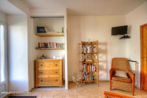 a room with a book shelf and a chair and a dresser at U san larenzu in Aullène