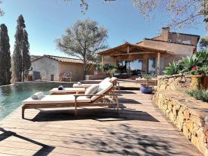 a pool with chaise lounges on a wooden deck next to a house at Casa penisula in Porto-Vecchio