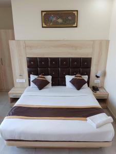 a bedroom with a large bed with a leather headboard at Hotel SS Grand in Lucknow