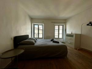 a bedroom with a bed with a table and two windows at Studios Citadelle in Parthenay