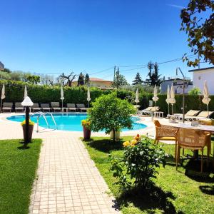 a swimming pool with tables and umbrellas in a yard at Hotel Eden in Bardolino