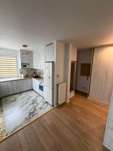an empty kitchen with a white refrigerator and wooden floors at Anuszka Apartament 3 in Gdynia