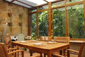 a wooden table and chairs in a room with windows at Casa Príncipe 12 in Cambados