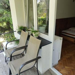 a porch with three chairs and a table and a window at Kwatery u Gabrieli in Włodzimierzów