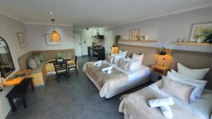 a bedroom with two beds and a desk and a couch at Point Village Hotel and Self Catering in Mossel Bay