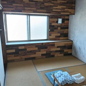 a room with a wall made out of reclaimed wood at Hakodate Guest House in Hakodate