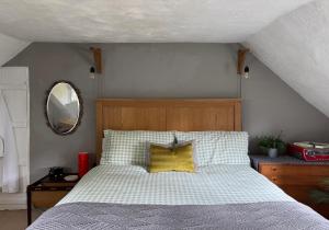 a bedroom with a bed with a yellow pillow and a mirror at 3 Bedrooms, 3 Double Beds, 6 Guests, Countryside Thatched Cottage in Four Marks