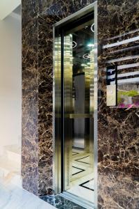 a glass elevator in a room with a marble wall at LUNA House in Can Tho