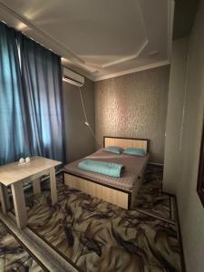 a small bedroom with a bed and a table at SaYAHAT TIMES in Türkistan