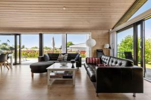 a living room with leather furniture and large windows at S749-Stroby-Nattergalevej-9 in Strøby