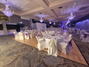 a banquet hall with white tables and chairs and chandeliers at Treacys West County Conference and Leisure Centre in Ennis +43 photos