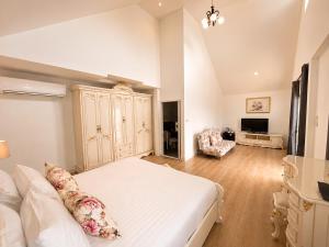 a bedroom with a white bed and a living room at Kenikar Raintree Resort Chumphon in Chumphon