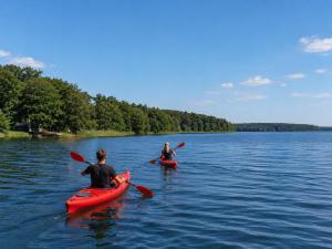 two people in kayaks in the water on a lake at Ferienhaus am See mit Sauna in Rheinsberg