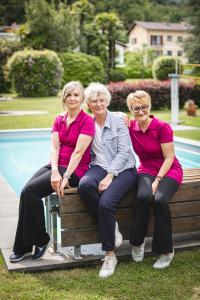 three women sitting on a bench next to a pool at Villa Siesta, Park & Pool Living in Losone