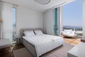 a white bedroom with a bed and a chair at Penthouses 42 Residence by Brown in Eilat +32 photos