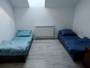 two beds in a room with blue sheets at Pod Lasem in Altanka
