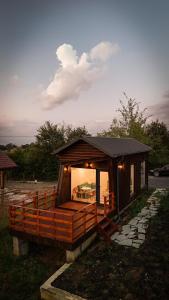 a small cabin with a porch in the grass at SkyAtlas Hideaway in Sohodol