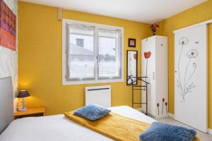 a bedroom with yellow walls and a bed with blue pillows at Le Cyclamens - MC et JC in Onet le Château