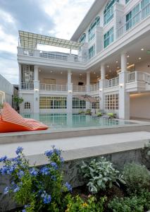 Außenansicht eines Gebäudes mit Pool in der Unterkunft De Hug Hotel & Residence in Chiang Rai