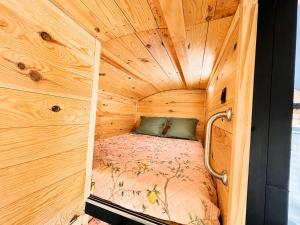 a small room with a bed in a wooden cabin at Roulotte Cowboy - Tiny House insolite in Mignaloux-Beauvoir +4 photos