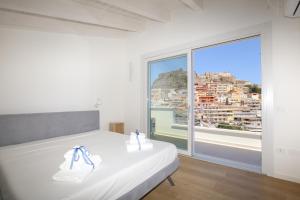 a bedroom with a white bed and a large window at Suite HollidayHouse - vista mare in Castelsardo