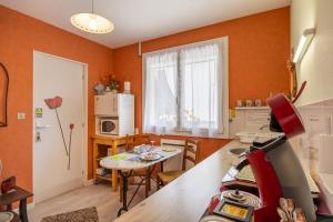 a kitchen with orange walls and a table and a kitchen with a dining room at Le Cyclamens - MC et JC in Onet le Château