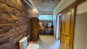 a bathroom with a brick wall and a toilet at Green Haven Homestay in Tetebatu