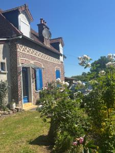 a brick house with blue windows and a bush at Gîte de campagne in Candor