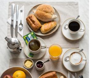 a table with plates of breakfast food and cups of coffee at Hotel Adelaide in Faro +18 photos
