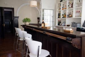 a bar with white chairs and bottles of alcohol at Las Carolinas Garden in Santander