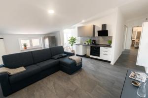 a living room with a black couch and a kitchen at Fiorucci Apartments - Marco's House in Focene