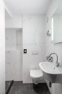 a white bathroom with a toilet and a sink at Hotel Mansion in Amsterdam +22 photos