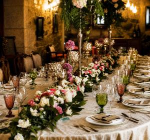 a long table with white and pink flowers on it at Hotel Pazo Do Souto in Carballo +101 photos