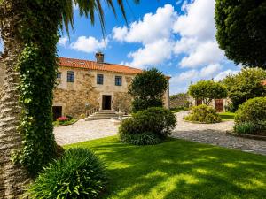 an old stone house with a palm tree at Hotel Pazo Do Souto in Carballo