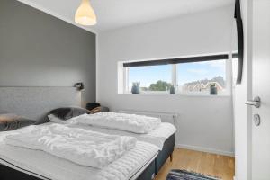 a bedroom with a bed with white sheets and a window at 0385-Romo-Hollaenderstraedet-42 in Høm