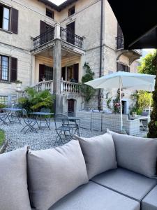 a couch and an umbrella in front of a building at Villa il Maiale Bianco Bed & Breakfast in San Fedele Intelvi