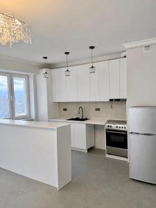 a white kitchen with a sink and a refrigerator at White Residency in Yerevan