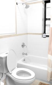 a white bathroom with a toilet and a bath tub at Beachh - 2Beach Home - Blue3090 in Brooklyn