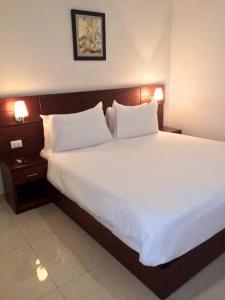 ein Schlafzimmer mit einem großen Bett mit weißer Bettwäsche und Kissen in der Unterkunft Hotel Bella Riva Kinshasa in Kinshasa