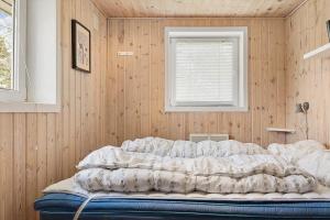 a bed in a room with a wooden wall at 0416-Romo-Dyssebjergvej-13 in Høm