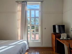 a bedroom with a bed and a television and a window at Las Carolinas Garden in Santander