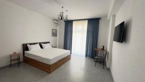 a white bedroom with a bed and a television at Humor Hotel in Tashkent