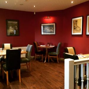 a dining room with red walls and tables and chairs at The Craven Arms in Settle