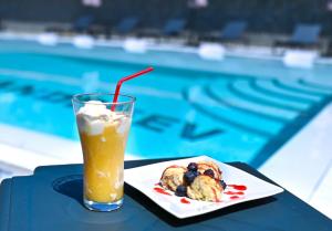 a drink and a plate of food next to a swimming pool at Family hotel Andreev in Dobrinishte