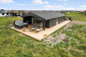 a black house with chairs and a couch on a deck at 381-Harboore-Slettevej-32 in Harboør