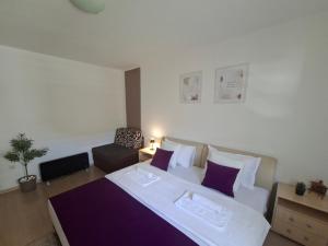 a bedroom with a large white bed with purple pillows at Apartments Platz in Mostar